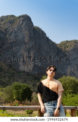 Asian man wear sunglass travel relax in the holiday. look at camera on the Moutain background
