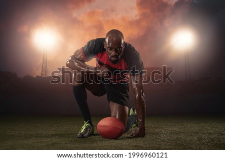Power, energy. Professional male rugby player posing isolated on stadium background. African fit athlete preparing for match. Concept of health, sport, action, motion, competition.
