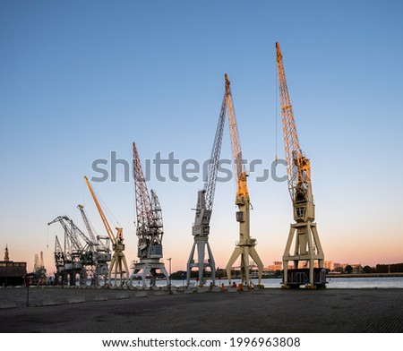 Old harbor cranes in early morning sunlight. The cranes are part of the collection of the MAS museum. Royalty-Free Stock Photo #1996963808