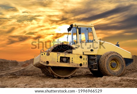 Soil Compactor for leveling ground for the foundation and on road construction. Road compaction equipment at construction site. Vibration single-cylinder road roller on amazing sunset background. Royalty-Free Stock Photo #1996966529