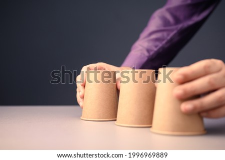 Closeup man going to take turn the cups in shell game, three thimbles guessing game, concept for tricks, chance, solution and making decision
