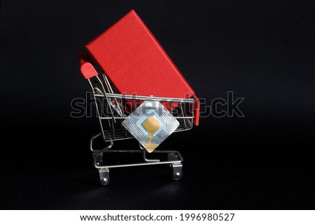 Supermarket trolley with red box and RFID tag transponder. The concept of using RFID technology in trade to identify goods and prevent shoplifting. Picture for warning shoplifters. Black background