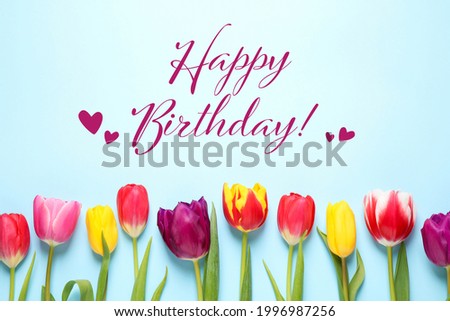 Happy Birthday! Beautiful tulips on light blue background, flat lay.