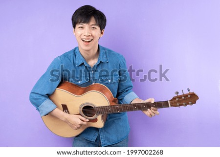 Portrait of Asian man in blue shirt posing on purple background
