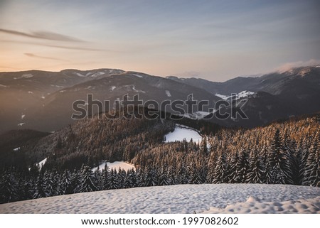 Orange sky sunset in Austrian alps, mountains with snow in winter