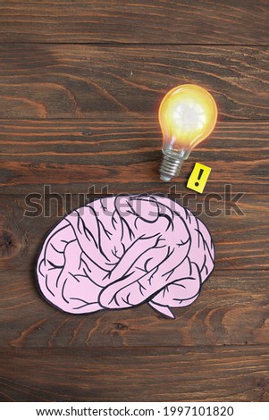 drawn cartoon human brain with glowing light bulb on wooden background. creative concept brainstorm. business idea creation