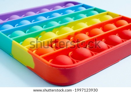 Close-up of the popular children's toy pop It fidget. Copy space. New popular silicone colorful pop It game in the form of rectangular isolated on a blue background. View in above. Anti-stress. Royalty-Free Stock Photo #1997123930