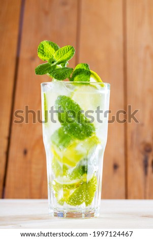 Mojito cocktail on wooden boards. Summer cocktail in the rustic style. Refreshing drink with lime, mint and ice. Trendy beverage