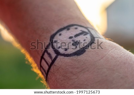 Natural light. a human hand on it is a clock drawn in black marker. Close-up.