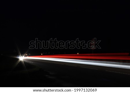 Night photo of passing cars on the road. Limited speed. Beware of pedestrians. Slow shutter speed. Focus on road sign.
