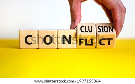 Conflict or conclusion symbol. Businessman turns wooden cubes, changes the word 'conflict' to 'conclusion'. Beautiful yellow and white background, copy space. Business, conflict or conclusion concept. Royalty-Free Stock Photo #1997155064