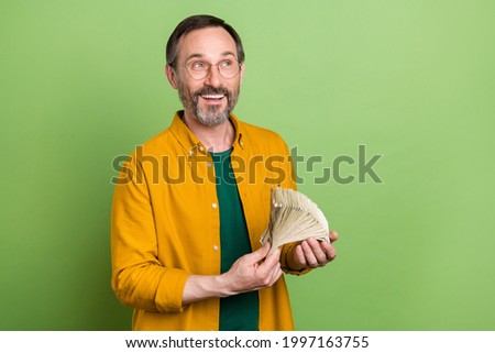 Photo of mature business man happy positive smile hold cash dollars money rich look empty space isolated over green color background