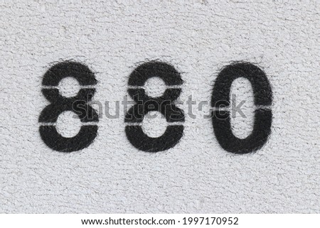 Black Number 880 on the white wall. Spray paint. Number eight hundred and eighty.