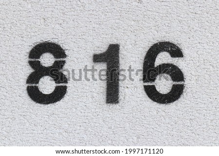 Black Number 816 on the white wall. Spray paint. Number eight hundred and sixteen.