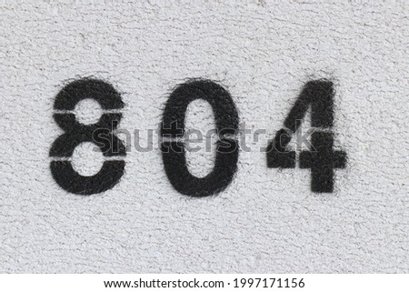 Black Number 804 on the white wall. Spray paint. Number eight hundred four.