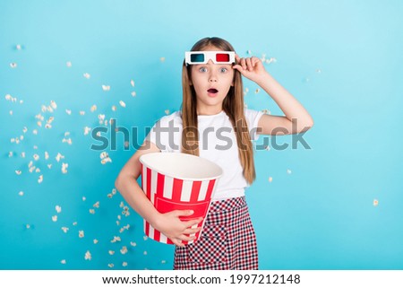 Photo of impressed blond hair small girl with pop corn wear eyewear white t-shirt isolated on blue color background