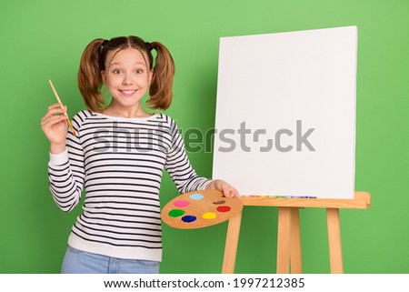 Photo of impressed tail hairstyle little girl hold brush paint wear striped sweater isolated on green color background