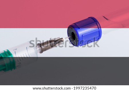 Yemen flag on the background of a medical bottle for injection and syringe for vaccination. Coronavirus vaccine