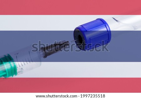 Thailand flag on the background of a medical bottle for injection and syringe for vaccination. Coronavirus vaccine