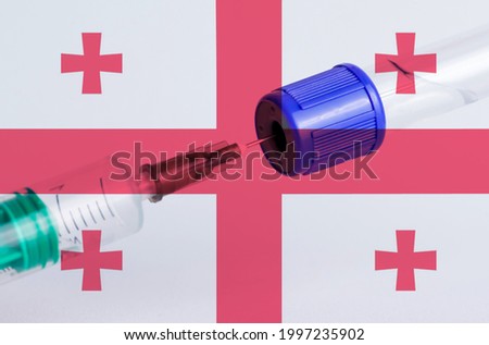 Georgia flag on the background of a medical bottle for injection and syringe for vaccination. Coronavirus vaccine