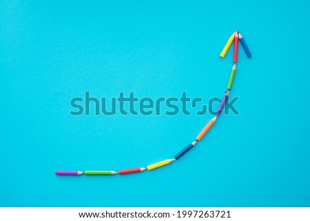 Flat lay of color pencils curve graph growth up form on blue background with copy space. Business growth, creative idea, kids art education and development concept. Royalty-Free Stock Photo #1997263721