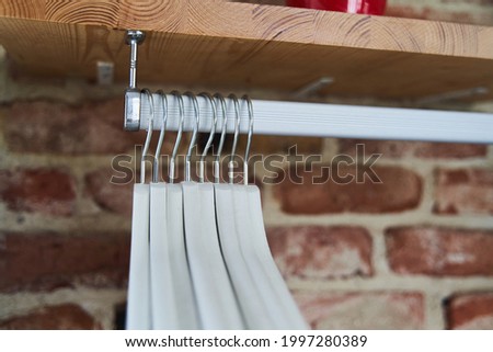 Many wooden white hangers on a rod. Store concept, sale, design, empty hanger. High quality photo