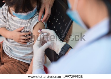 Doctor administrating COVID-19 Vaccine to a Child patient at the School. First safe and effective coronavirus Vaccine,