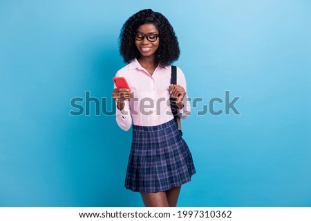 Photo portrait of smiling woman in glasses keeping rucksack browsing information smartphone isolated vivid blue color background