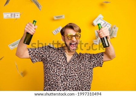 Photo of funky drunk young gentleman dressed print shirt glasses money flying holding beer bottles isolated yellow color background