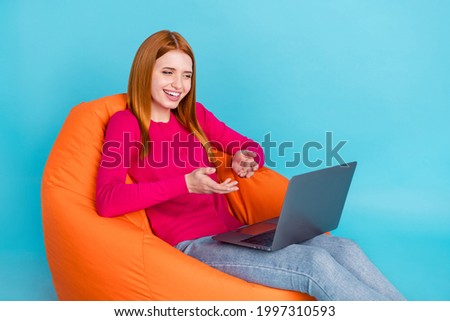 Full length photo of pretty shiny lady dressed pink outfit smiling sitting bean bag talking modern device isolated blue color background