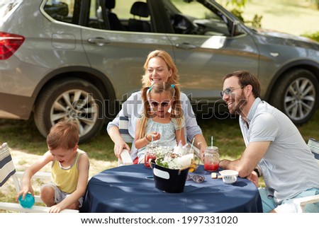 cheerful caucasian family of four sitting at table outdoor, having fun