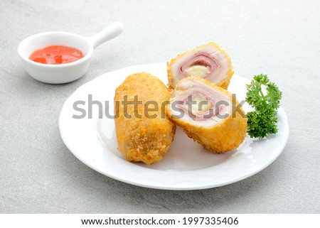 Crispy Cordon Blue, Chicken fillet roll with ham and cheese. Served in white plate on grey background.  Royalty-Free Stock Photo #1997335406