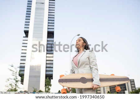 business woman in the city mature woman in suit, buildings skate board.
