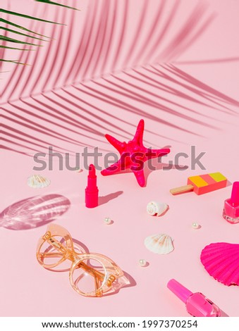 Summer scene with starfish, lipstick, nail lacquer, ice cream, seashell and sunglasses on a pastel pink background. Tropical palm leaf shadow. Creative summer vacation concept.