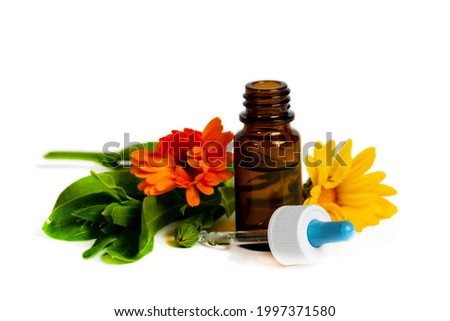 marigold orange and yellow flowers with opened brown bottle and dropper on white background