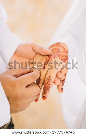 a lovely moment when a bride put a ring on a beautiful henna art finger of his wife. 