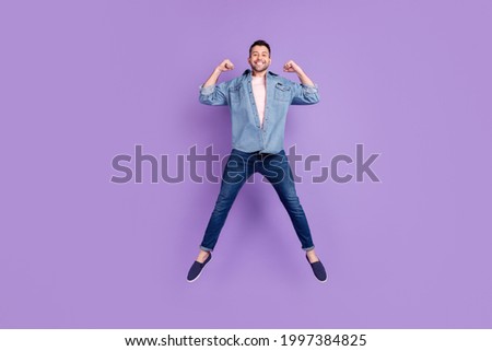 Full length body size photo man smiling jumping up showing biceps isolated pastel violet color background