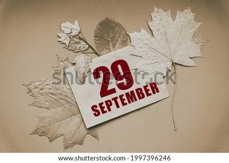 september 29. 29th day of month, calendar date.Envelope with the date and month, surrounded by autumn leaves on brown background. Day of year concept.