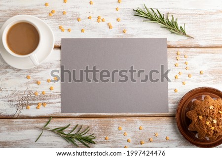 Gray paper sheet mockup with cup of coffee and cake on white wooden background. Blank, top view, flat lay, still life.