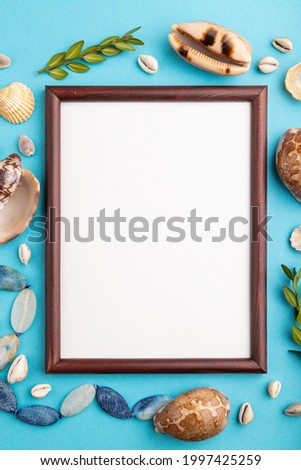 Composition with wooden frame, seashells, green boxwood. mockup on blue pastel background. Blank, top view, still life, flat lay, copy space. travel concept.