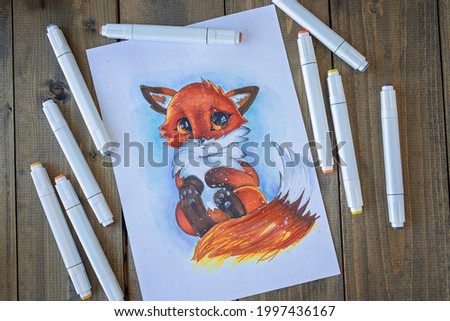 Flat lay with sketching ittle red-haired cute fox with a bushy tail. All placed on wooden table picture and markers. Hobby. Drawing fox. Top view. Soft focus