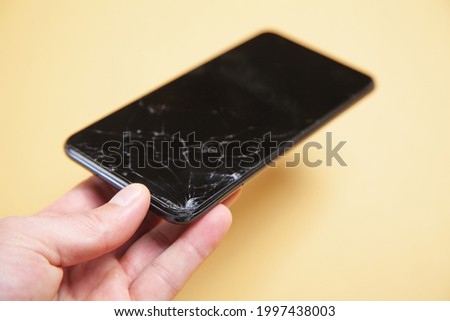 Man holding black broken smartphone. Broken screen
