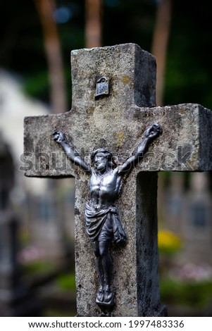 Jesus figurine on the cemetery cross. Picture taken in a soft light, shaded place.