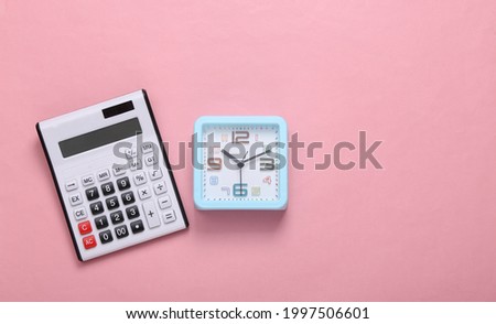 Calculator and alarm clock on a pink background. Top view