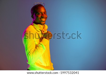 Portrait of young African handsome man isolated over gradient background in neon light. Vibrant colors. Concept of human emotions, facial expression, youth. Copy space for ad.