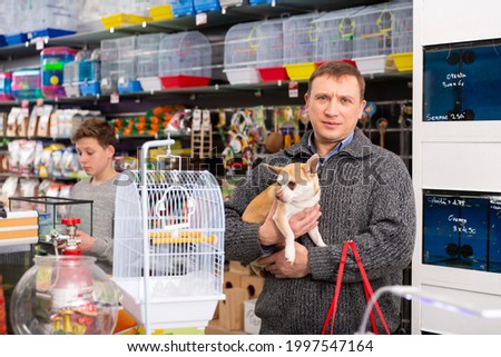 Portrait of adult man with dog in petshop, boy on background. High quality photo