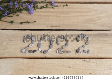 2022 logo lined with sea stones and blue cornflowers 2022