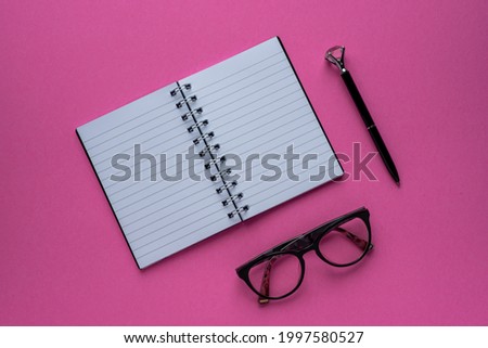 Photography of notebook, glasses, pen, pink background