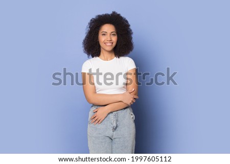 Portrait of happy millennial African American female in casual clothes isolated on blue studio background. Smiling young mixed race woman modern or actress pose shoot. Diversity concept.