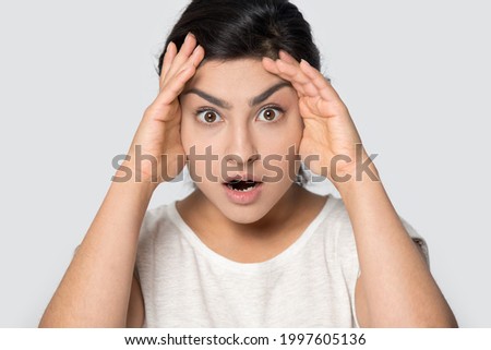 Close up portrait of shocked young Indian woman isolated on grey studio background hear unexpected unbelievable news. Stunned mixed race female surprised by sale offer or promotion deal.